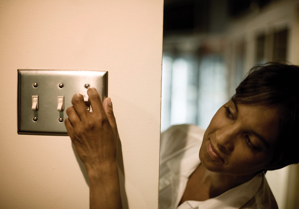 turning-off-lights woman flipping light switch